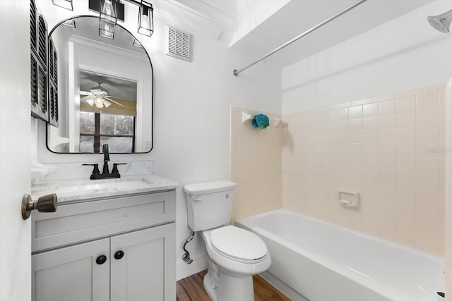 full bathroom with hardwood / wood-style floors, tiled shower / bath, vanity, and toilet