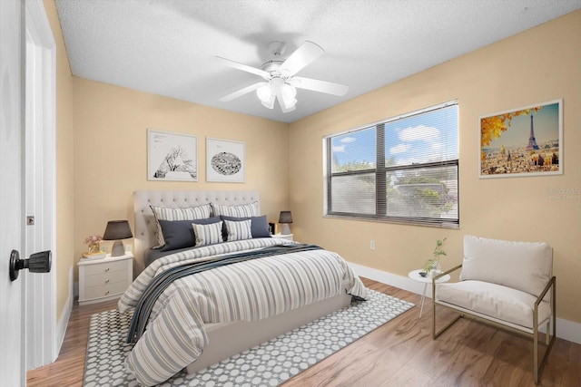 bedroom featuring a textured ceiling, ceiling fan, and light hardwood / wood-style flooring