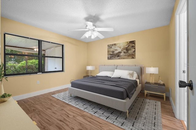 bedroom with ceiling fan, hardwood / wood-style floors, and a textured ceiling