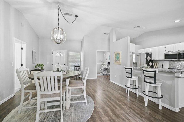 dining space with dark hardwood / wood-style flooring, lofted ceiling, and a notable chandelier