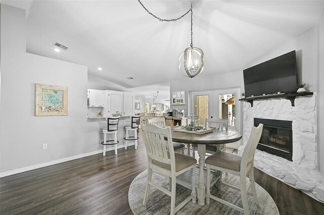 dining space featuring dark hardwood / wood-style flooring, a fireplace, and vaulted ceiling