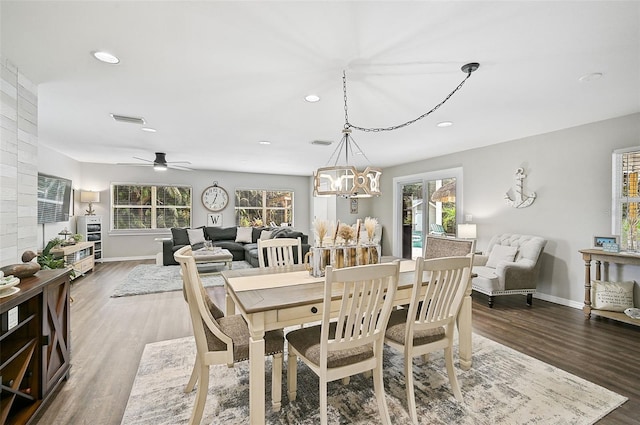 dining room featuring ceiling fan with notable chandelier and dark wood-type flooring