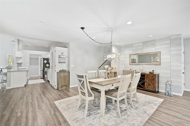 dining space featuring light wood-type flooring and an inviting chandelier