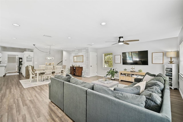 living room with wood-type flooring and ceiling fan with notable chandelier