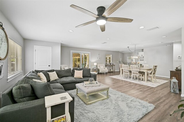 living room with wood-type flooring, ceiling fan with notable chandelier, and a healthy amount of sunlight