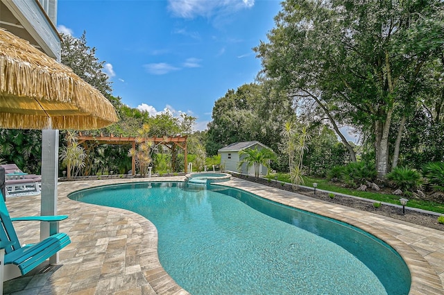 view of pool featuring a patio area, an in ground hot tub, and a storage shed