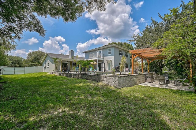 rear view of property featuring a yard, a pergola, a balcony, and a patio area