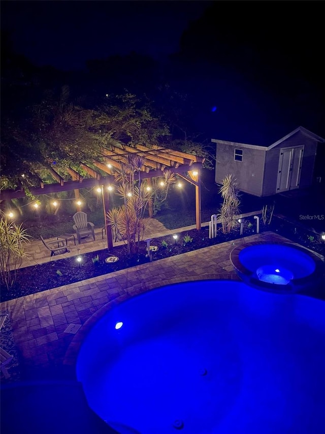 pool at twilight featuring an in ground hot tub and a patio