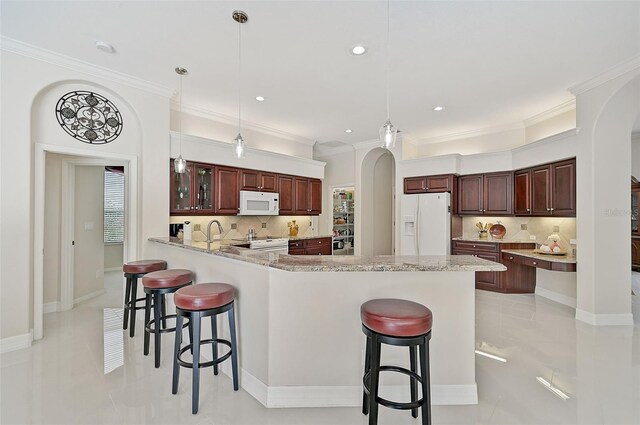 kitchen with kitchen peninsula, pendant lighting, white appliances, and backsplash