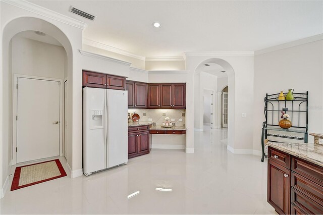 kitchen with light stone countertops, white fridge with ice dispenser, light tile patterned floors, and crown molding