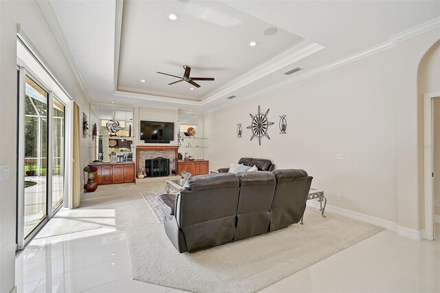 living room featuring a raised ceiling, ceiling fan, crown molding, and light tile patterned floors