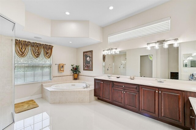 bathroom with tile patterned flooring, a relaxing tiled tub, and vanity