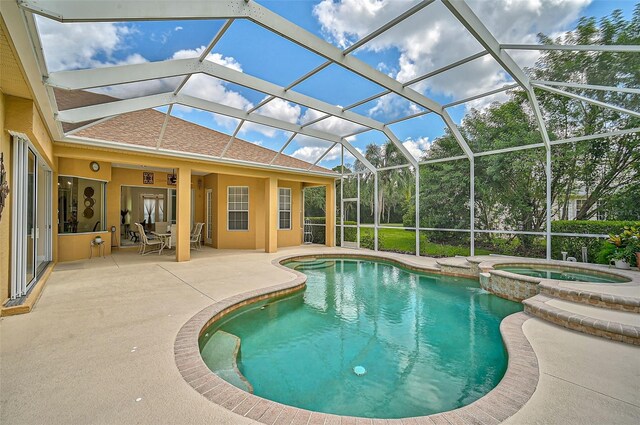 view of pool with glass enclosure, an in ground hot tub, and a patio