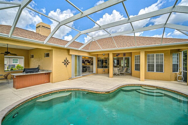 view of pool with glass enclosure, ceiling fan, and a patio