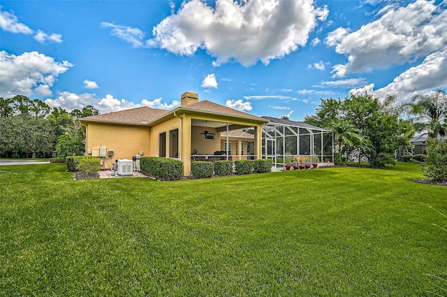 rear view of house featuring central AC, ceiling fan, a lanai, and a lawn