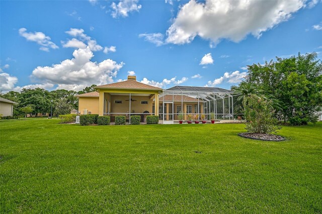 back of property with a lawn, glass enclosure, and ceiling fan