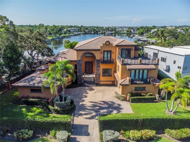 mediterranean / spanish-style home featuring a balcony, a front yard, and a water view