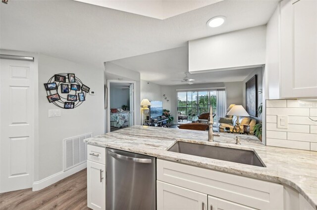 kitchen featuring dishwasher, white cabinets, sink, light hardwood / wood-style flooring, and light stone countertops