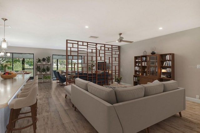 living area with recessed lighting, visible vents, baseboards, and wood finished floors