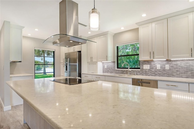 kitchen featuring island range hood, a sink, white cabinetry, stainless steel fridge with ice dispenser, and pendant lighting