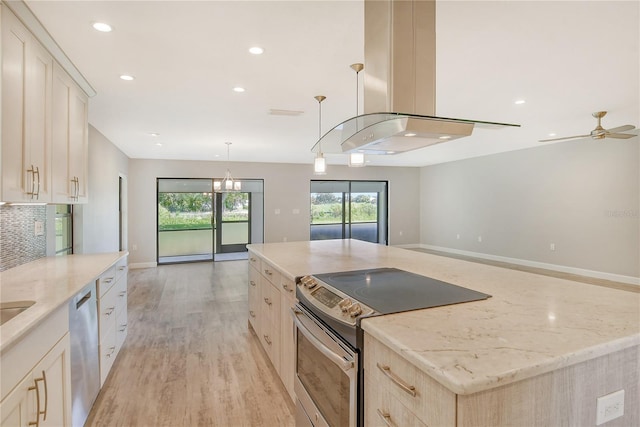 kitchen with island range hood, appliances with stainless steel finishes, a kitchen island, decorative light fixtures, and ceiling fan with notable chandelier