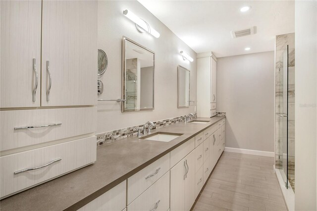 bathroom with a shower, backsplash, vanity, and wood-type flooring