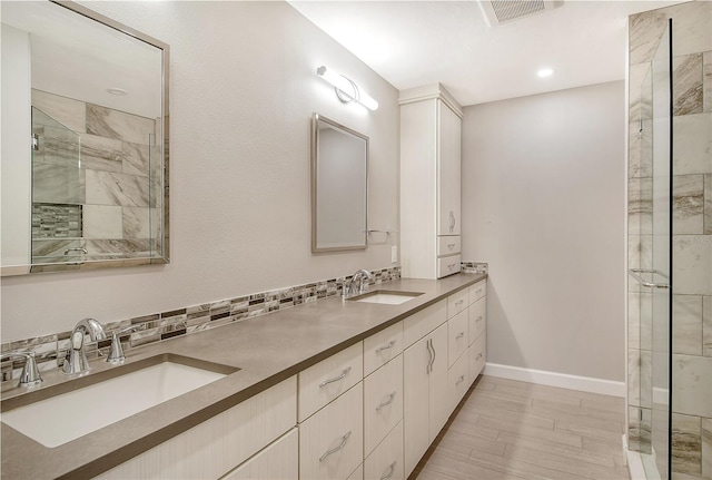 bathroom featuring hardwood / wood-style flooring, tiled shower, tasteful backsplash, and vanity