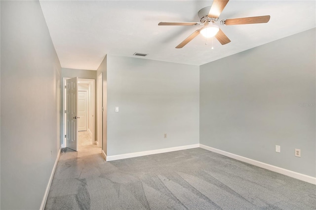 empty room featuring a ceiling fan, visible vents, light carpet, and baseboards