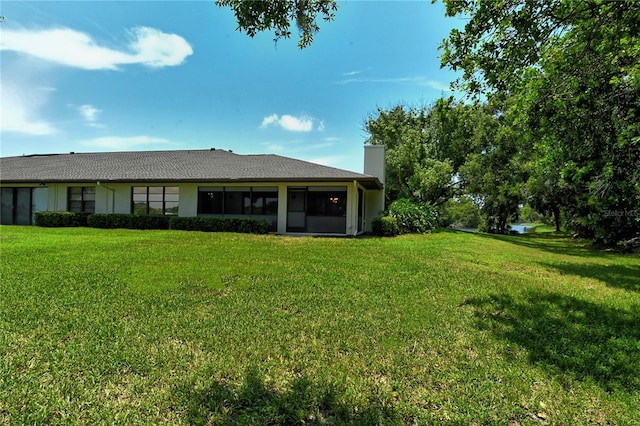 rear view of property with a yard, a chimney, and stucco siding