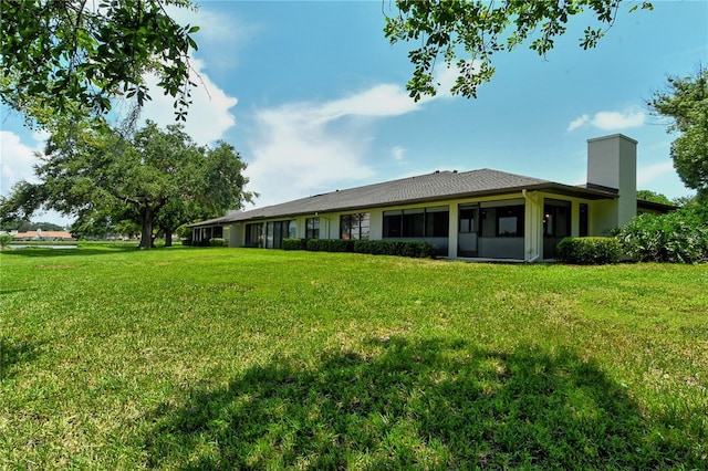 rear view of property featuring a yard and a chimney