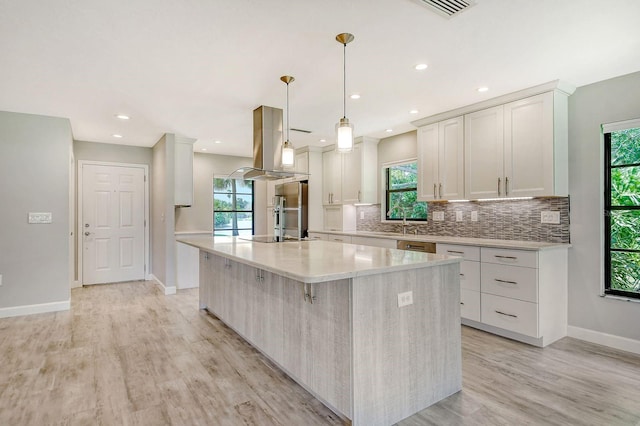 kitchen with hanging light fixtures, a center island, island exhaust hood, light wood-type flooring, and white cabinets