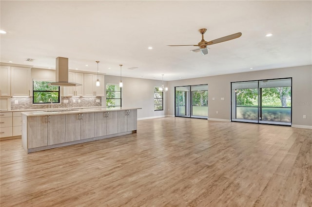 kitchen with a large island, ceiling fan, island exhaust hood, light hardwood / wood-style flooring, and hanging light fixtures