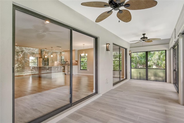 unfurnished sunroom featuring a wealth of natural light and ceiling fan with notable chandelier