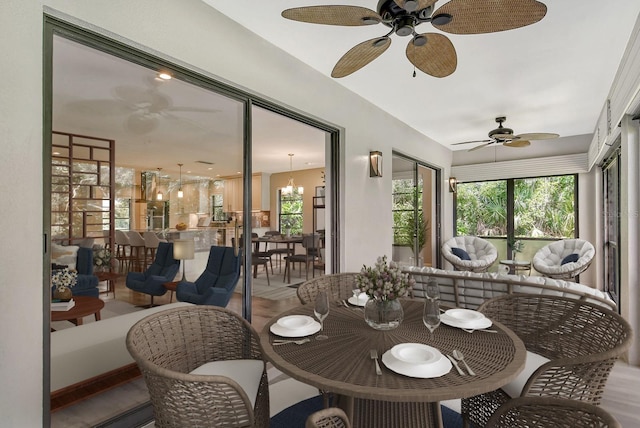 sunroom featuring ceiling fan with notable chandelier