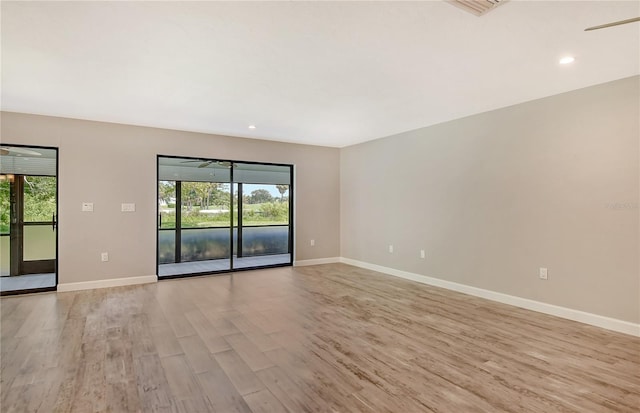 spare room with light wood-type flooring, plenty of natural light, and baseboards