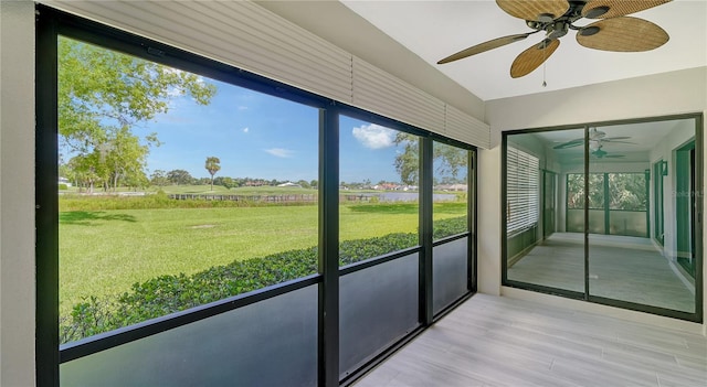 unfurnished sunroom with ceiling fan and a rural view