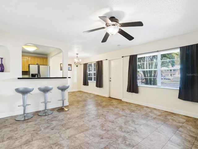 kitchen with light brown cabinetry, ceiling fan with notable chandelier, fridge with ice dispenser, a breakfast bar, and light tile patterned floors