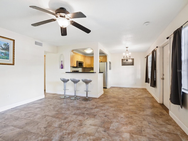 kitchen featuring light tile patterned flooring, light brown cabinetry, ceiling fan with notable chandelier, a breakfast bar area, and appliances with stainless steel finishes