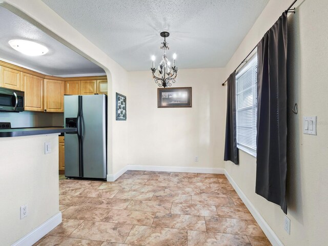 kitchen with a chandelier, a textured ceiling, stainless steel appliances, and light tile patterned floors