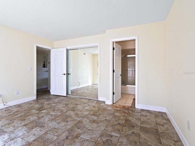 unfurnished bedroom featuring ensuite bath, tile patterned flooring, and a closet