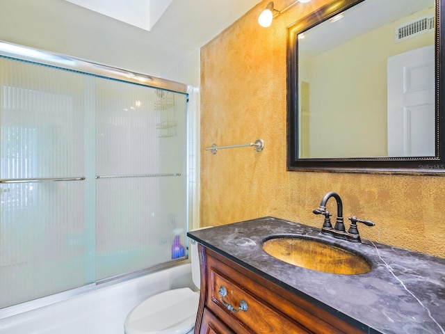 full bathroom with combined bath / shower with glass door, toilet, and vanity