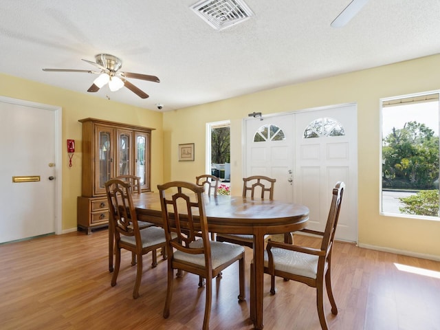 dining room with a healthy amount of sunlight, a textured ceiling, light wood-type flooring, and ceiling fan