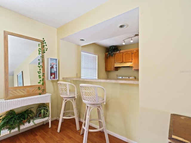 kitchen featuring kitchen peninsula, track lighting, hardwood / wood-style floors, and a textured ceiling