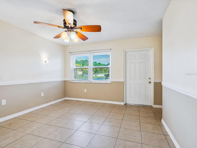 tiled spare room with a textured ceiling and ceiling fan