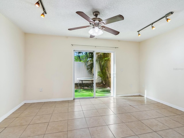 tiled empty room with rail lighting, a textured ceiling, and ceiling fan