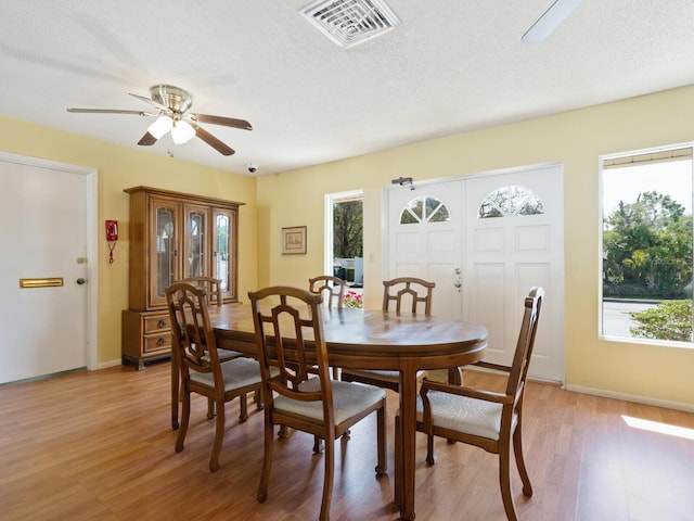 dining room featuring a healthy amount of sunlight, a textured ceiling, light wood-type flooring, and ceiling fan