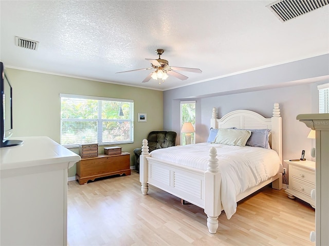 bedroom featuring a textured ceiling, light hardwood / wood-style flooring, ornamental molding, and ceiling fan