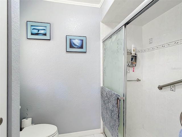 bathroom with a shower with door, toilet, and ornamental molding