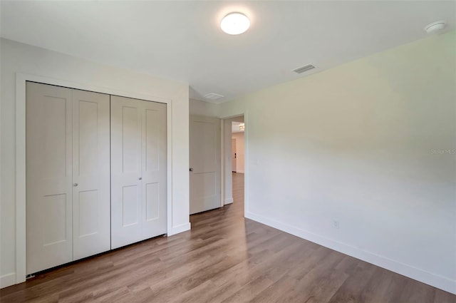 unfurnished bedroom with wood-type flooring and a closet