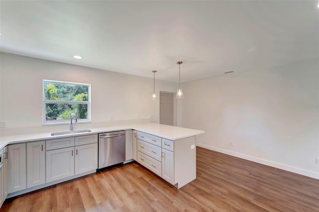 kitchen featuring light wood-type flooring, sink, dishwasher, and kitchen peninsula